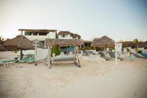 Tropical beach house on ocean shore among palm trees photo