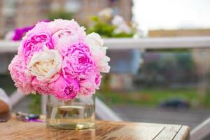 Charming bouquet of peonies in vase on table at restaurant photo