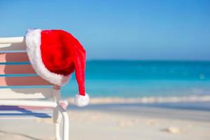 cerrar gorro de Papá Noel en silla longue en playa tropical foto