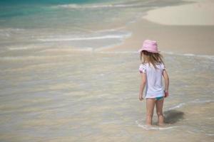 adorable niña jugando en aguas poco profundas en la playa perfecta foto