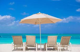 White umbrellas and sunbeds at tropical beach photo