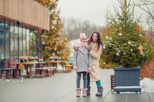 Little adorable girl with her mother skating on ice-rink photo