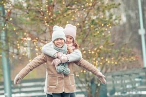 Adorable girls skating on ice rink outdoors in winter snow day photo