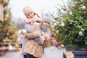 Adorable girls skating on ice rink outdoors in winter snow day photo