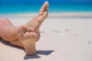 cerca de pies femeninos en la playa de arena blanca foto