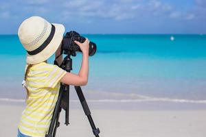 niña disparando con cámara en trípode durante sus vacaciones de verano foto