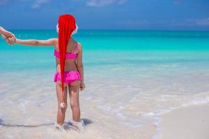 niña linda en sombrero rojo de santa en playa tropical foto