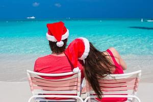Happy romantic couple in red Santa Hats at tropical beach photo