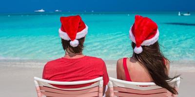 feliz pareja romántica con sombreros rojos de santa en la playa tropical foto