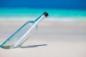 botella con un mensaje enterrado en la arena blanca foto