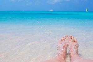 cerca de pies femeninos en la playa de arena blanca foto