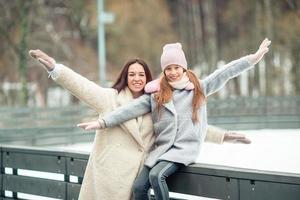 niña adorable con su madre patinando en la pista de hielo foto