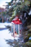 Christmas lantern with snowfall hanging on a fir branch photo