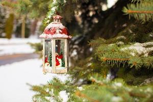 Christmas lantern with snowfall hanging on a fir branch photo