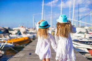 Adorable little girls walking in a port during summer vacation photo