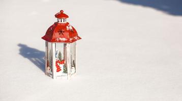 hermosa linterna roja de cuento de hadas en la nieve blanca en el bosque foto