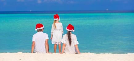 Happy family of three in Santa Hats on beach photo