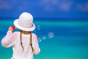 Adorable little girl making soap bubbles during summer vacation photo