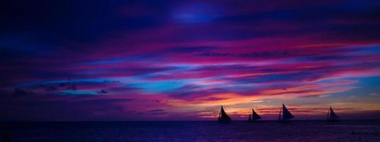 panorama de la hermosa puesta de sol colorida con velero en el horizonte en la isla de boracay foto