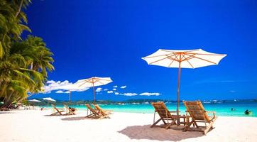 Paradise view of nice tropical empty sandy plage with umbrella and beach chair photo