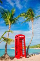 Red phone booth in Dickenson's bay Antigua. Beautiful landscape with a classic phone booth on the white sandy beach in Antigua photo