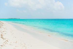 idílica playa tropical con arena blanca, aguas turquesas del océano y cielo azul en la isla caribeña foto