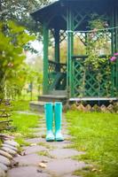 Bright fashionable rubber boots in the garden background of wooden pergolas photo