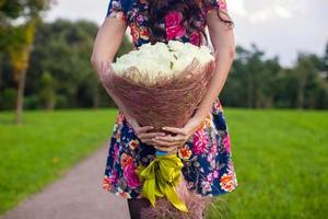 Incredibly beautiful large bouquet of white roses at the hands of a young girl in colored dress photo
