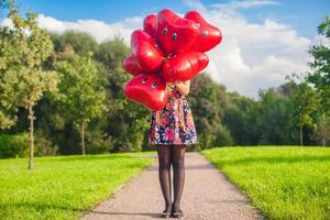 In the foreground, red balloons, followed by young woman at beautiful dress photo