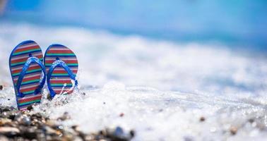 Blue flip flops on beach in front of the sea photo