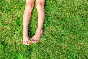Close-up of two legs of a young girl on the grass on the lawn photo