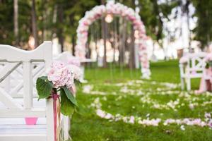 bancos de boda y arco de flores para ceremonia al aire libre foto