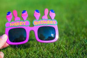 gafas rojas de feliz cumpleaños en la hierba foto