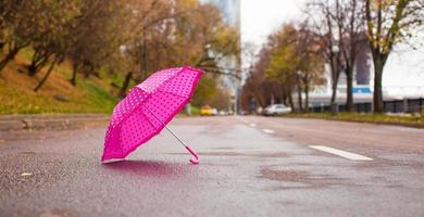 Pink children's umbrella on the wet asphalt outdoors photo