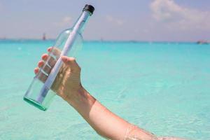 Bottle with a message in the hand background blue sky photo