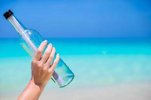 Bottle with a message in the hand background blue sky photo