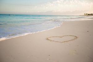 Heart painted in white sand on a tropical beach photo