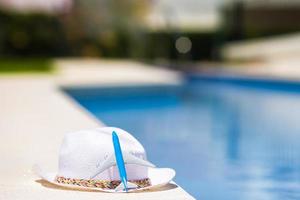 Aircraft small model and straw white hat near swimming pool at summer photo