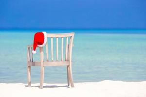 Red santa hat on beach chair at tropical vacation photo