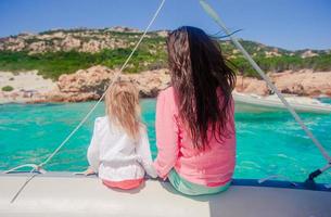 Young mother with her adorable little girl resting on a big boat photo