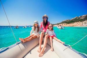 Young mother with her adorable little girls resting on a big boat photo