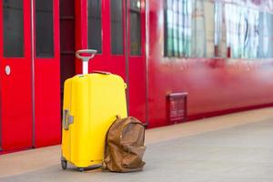 Yellow luggage with passports and brown backpack at train station photo