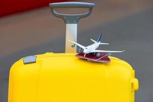 Primer plano de pasaportes rojos y modelo pequeño de avión en equipaje amarillo en la estación de tren foto