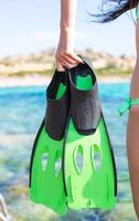 Diving goggles, snorkel and snorkeling fins at woman hands photo