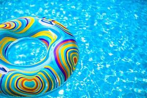 anillo de goma colorido inflable flotando en la piscina azul foto