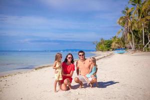 Young beautiful family of four enjoyed relaxing on the beach photo