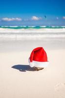 Santa Claus hat on the white sandy coast photo