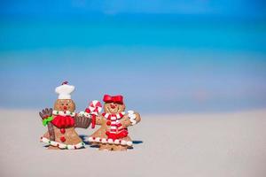 galletas de hombre de pan de jengibre de navidad en una playa de arena blanca foto