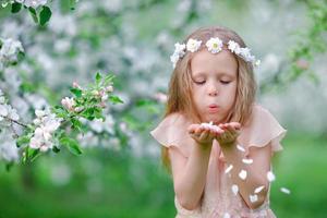 Adorable little girl in blooming tree garden on spring day photo