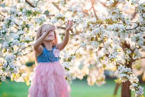 Little girl in blooming apple tree garden enjoy the warm day photo